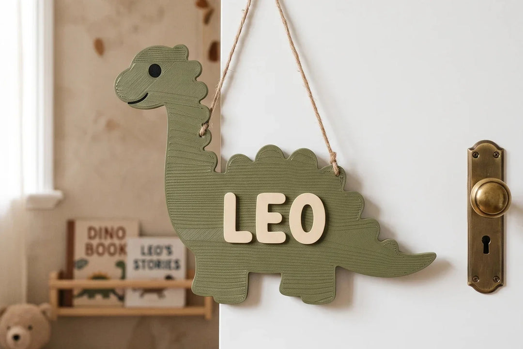 Placa con forma de dinosaurio y nombre en relieve colgada en la puerta de una habitación infantil