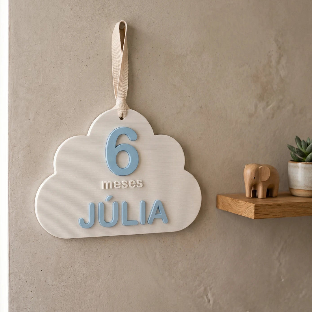 Tarjeta de cumple mes de bebé en forma de nube colgada de una cinta en una habitación infantil
