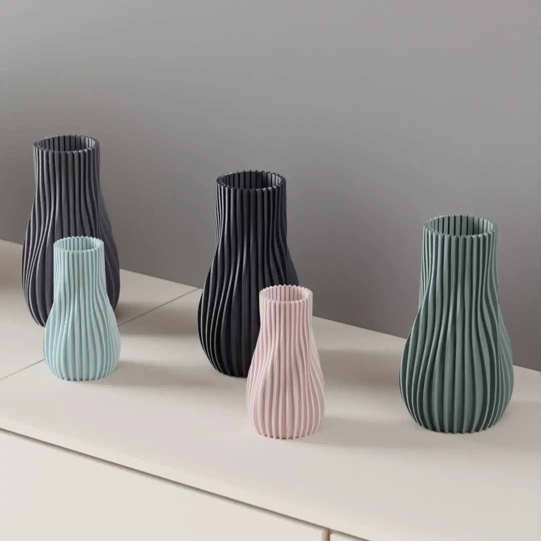 Jarrón decorativo de color gris carbón con diseño de lamas verticales onduladas y acabado mate sobre fondo blanco.