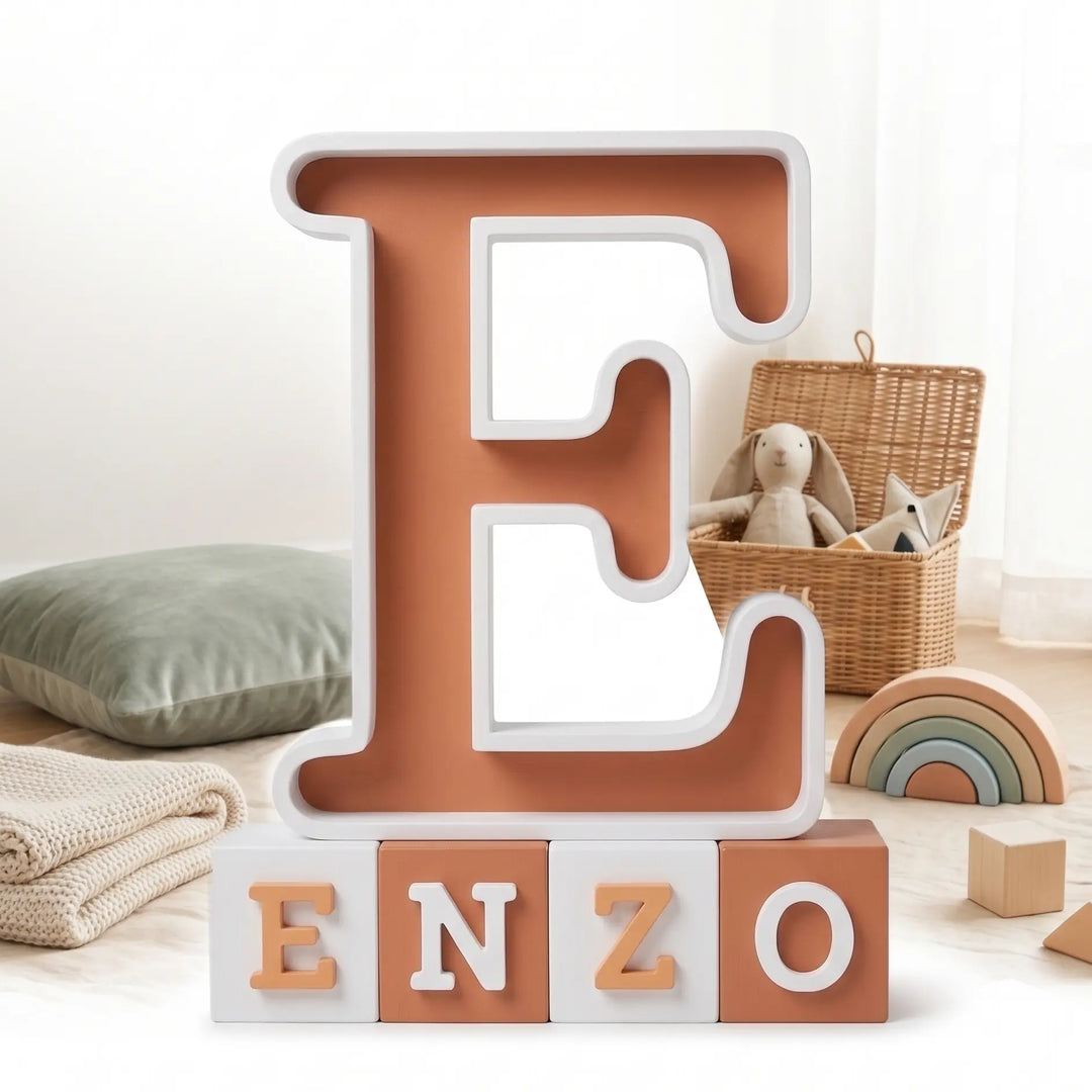 Letra E con el nombre Enzo en bloques de terracota y blanco en un rincón de juego infantil