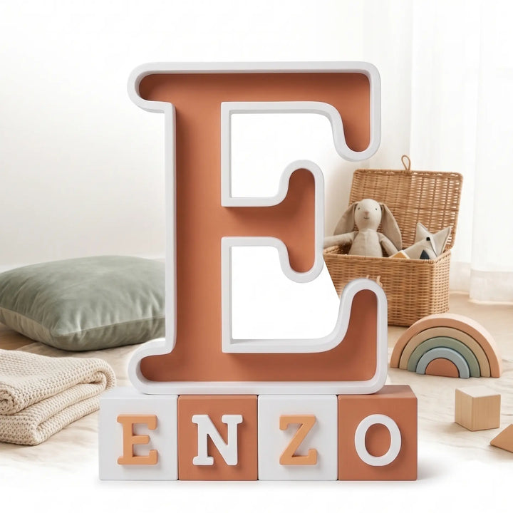 Letra E con el nombre Enzo en bloques de terracota y blanco en un rincón de juego infantil