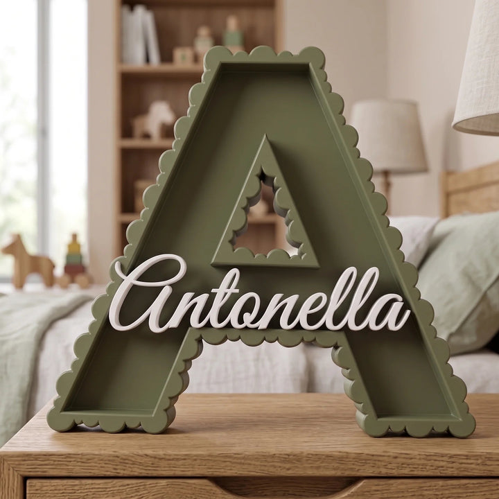 Letra A en verde oliva con el nombre Antonella sobre una mesita de madera en una habitación infantil