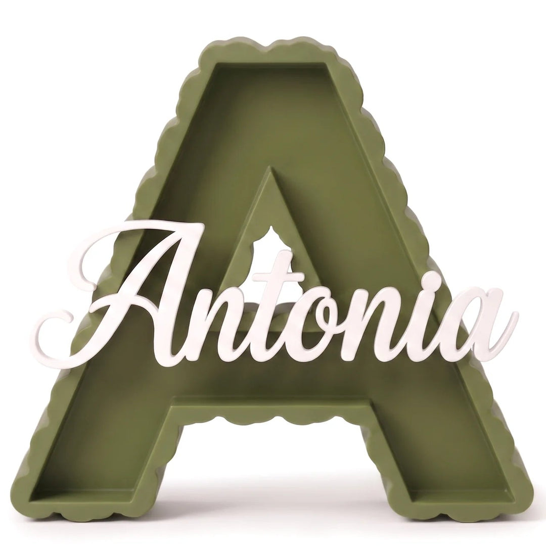 Letra A decorativa de contorno festoneado en verde oliva con el nombre Antonia en caligrafía blanca