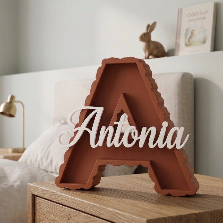 Letra A en terracota con el nombre Antonia sobre una mesilla de madera en una habitación infantil