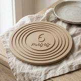 Tarjeta de cumplemés con anillos concéntricos en relieve sobre una cómoda de madera clara