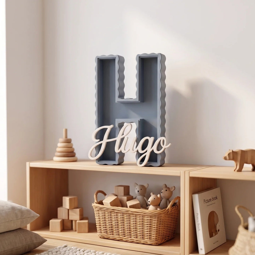 Letra H decorativa de ondas suaves con el nombre Hugo sobre una estantería baja de madera