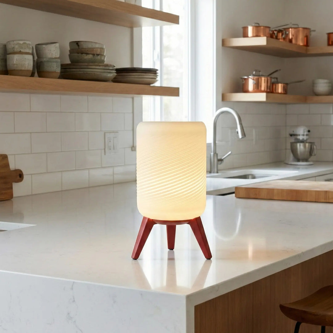 Lámpara de mesa con base trípode y pantalla cilíndrica de efecto espiral. Luz cálida difusa ideal para dormitorios y salones. Diseño contemporáneo y funcional.