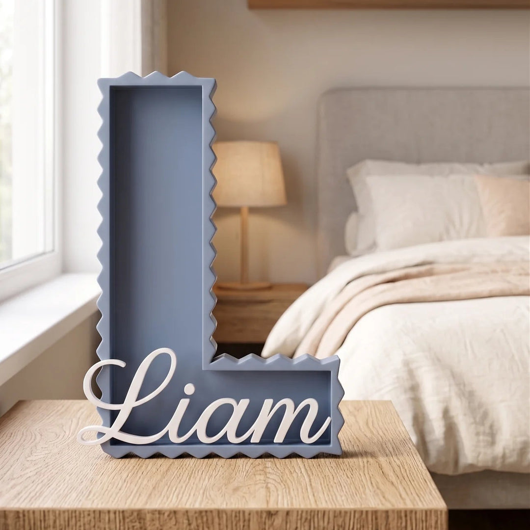 Letra L en zig zag azul con el nombre Liam sobre una mesita en una habitación infantil