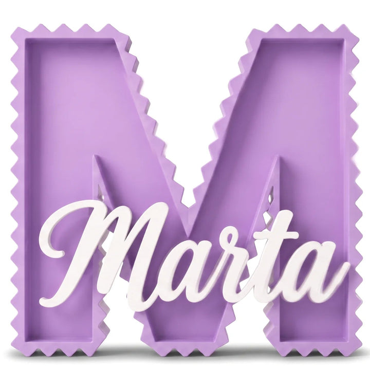 Letra M decorativa de contorno dentado en lila con el nombre Marta en caligrafía blanca