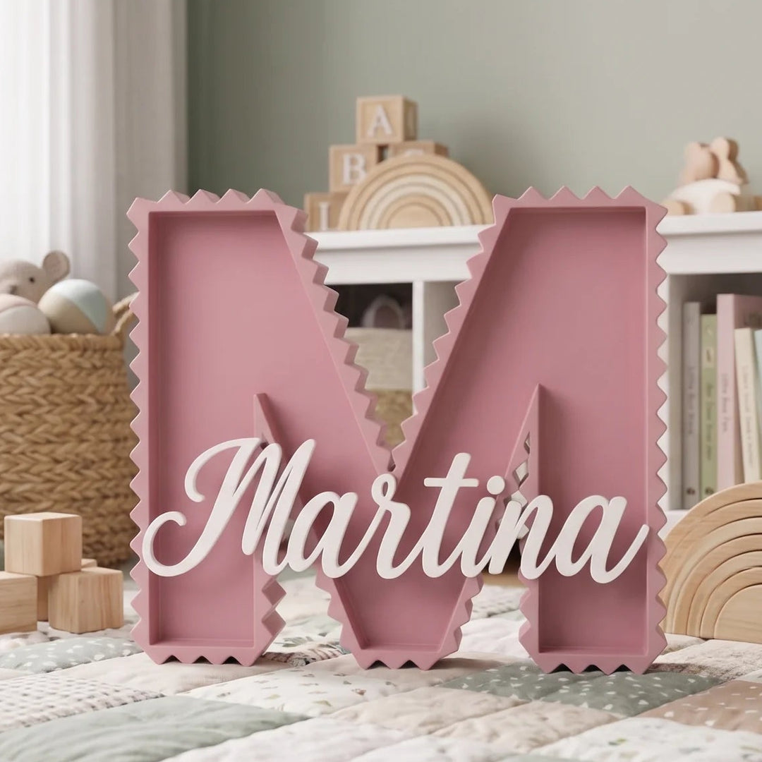 Letra M en zig zag rosa con el nombre Martina sobre una balda baja junto a juguetes de madera