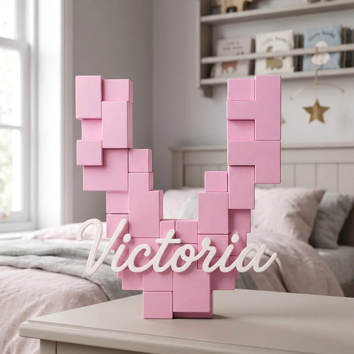 Letra V pixel rosa con el nombre Victoria sobre una cómoda en una habitación de niña