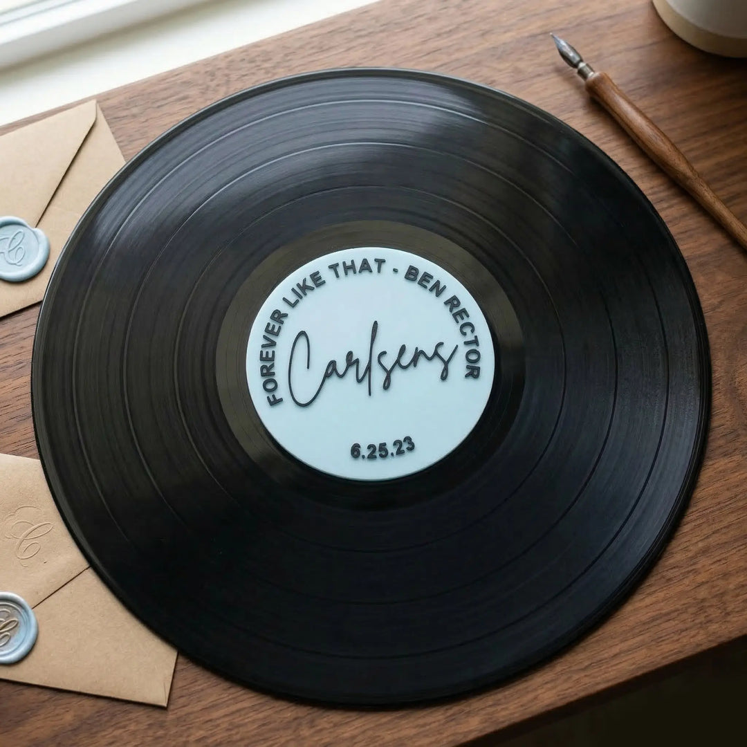 Vinilo conmemorativo personalizado con nombres y fecha sobre superficie de madera con accesorios de caligrafía